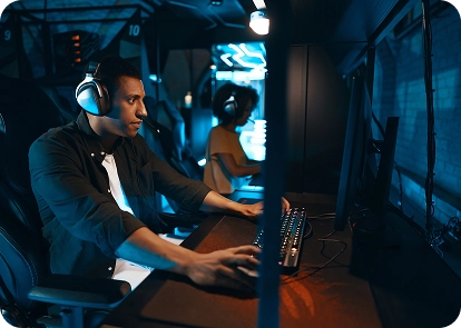 Een man met een koptelefoon zit achter de computer te gamen in een gameclub