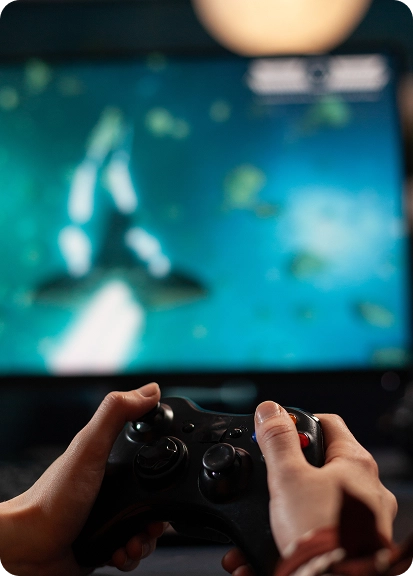 De handen van de speler houden de gamepad vast terwijl hij een videogame op het scherm speelt