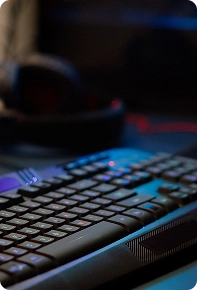 Close-up van een gamingtoetsenbord met RGB-verlichting in een donkere kamer, met een wazige achtergrond van de gamingopstelling